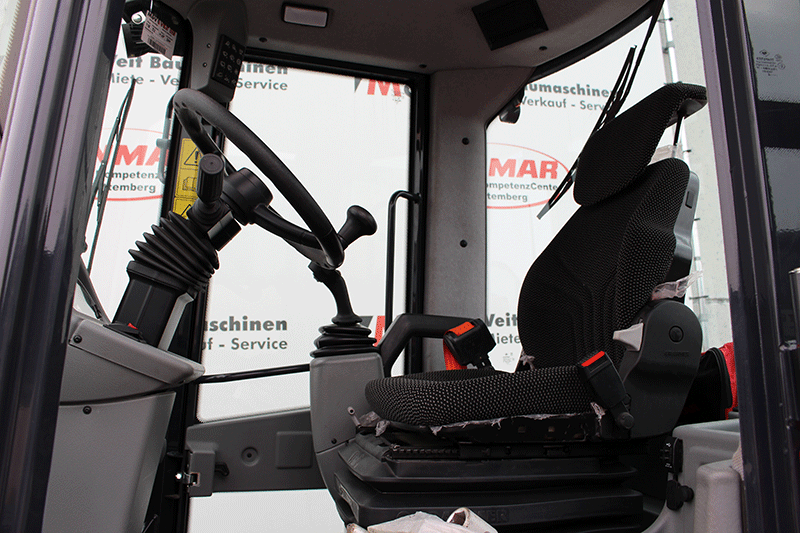Fahrerkabine des Yanmar V 70 Schwenkladers mit ergonomischem Fahrersitz, Joystick-Steuerung und großzügiger Rundumsicht für sicheres und komfortables Arbeiten im Baustelleneinsatz.