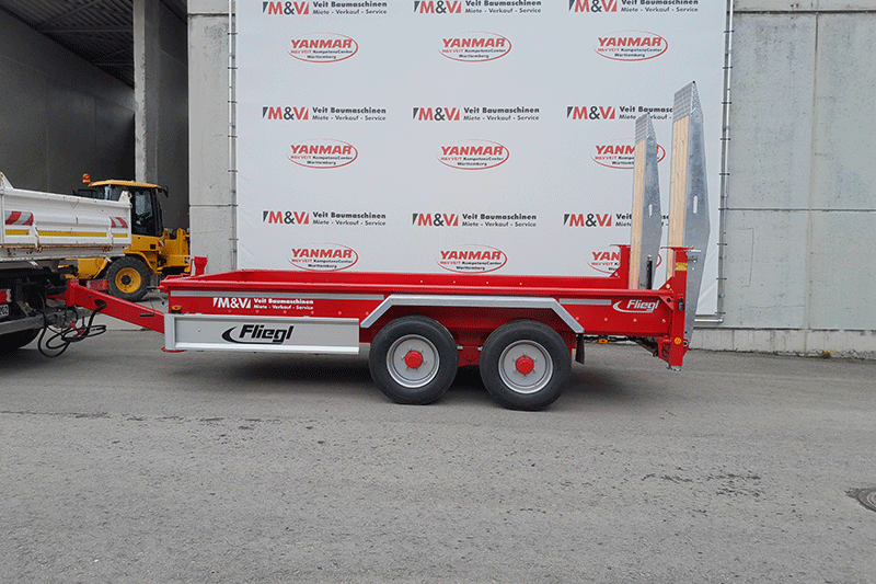 Seitenansicht des Fliegl TTS 89 Tandemanhängers mit robuster Rahmenkonstruktion, Tandemfahrwerk und großzügiger Ladefläche für den professionellen Maschinentransport.