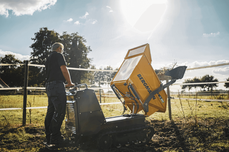 Mitarbeiter steht auf Trittbrett und nutzt Bergmann C901 Selbstlader Dumper in der Praxis